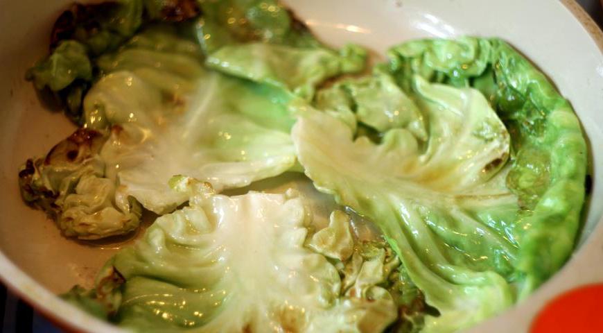 Капустные листья аккуратно отбейте при помощи деревянной скалки, слегка посолите и обжарьте на сковороде по паре минут с каждой стороны до мягкости и легкой румяности.