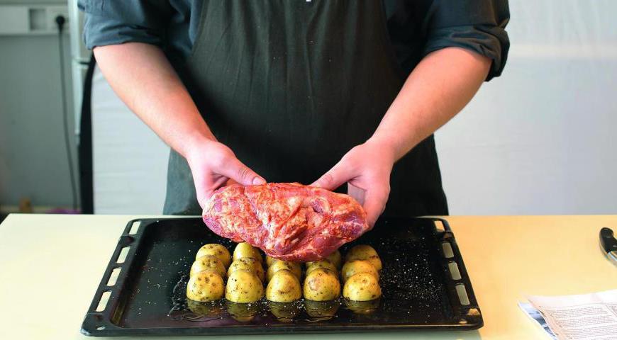 Растерите аджику с 1-3 столовыми ложками растительного масла и натрите мясо этой смесью со всех сторон. Втирайте маринад массирующими движениями. Уложите подготовленную шейку на половинки картофеля, уложенные в один слой срезом вниз в противне.