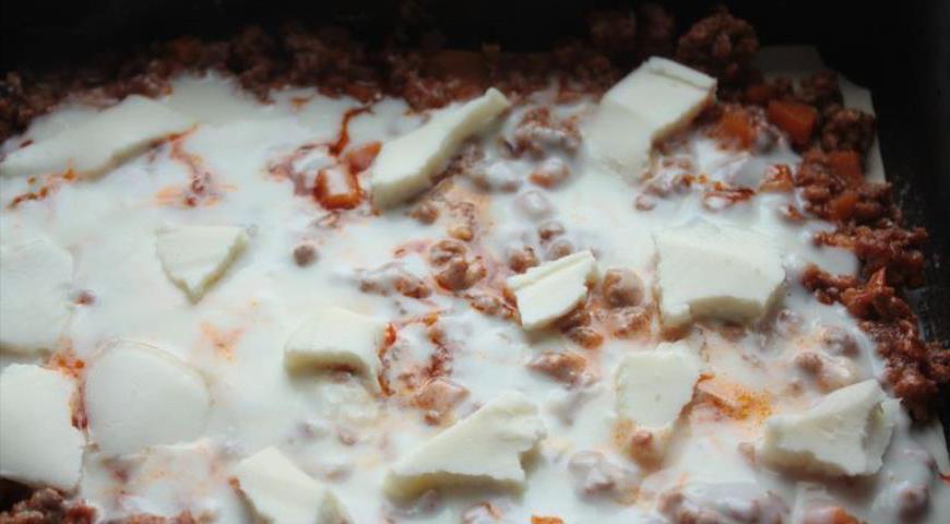 Выложите немного бешамеля на дно формы, затем слоями: тесто, мясное рагу, бешамель, Моцарелла. Повторите несколько раз, стараясь равномерно распределить начинку.