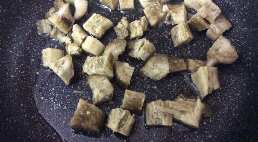 В сотейнике разогрейте растительное масло и выложите нарезанный кубиками баклажан. Обжаривайте его до легкой золотистости, чтобы он стал мягким.
