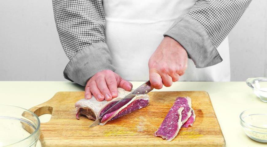Для удобства нарезки мясо можно предварительно слегка подморозить. Нарежьте его тонкими большими ломтиками. Приготовьте маринад, смешав вино с сахаром, и замаринуйте мясо на протяжении 25–30 минут.