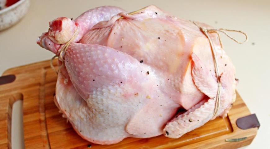 Свяжите ножки и крылья курицы кулинарной нитью, а место наполнения закрепите зубочистками, чтобы содержимое не выпало во время запекания.