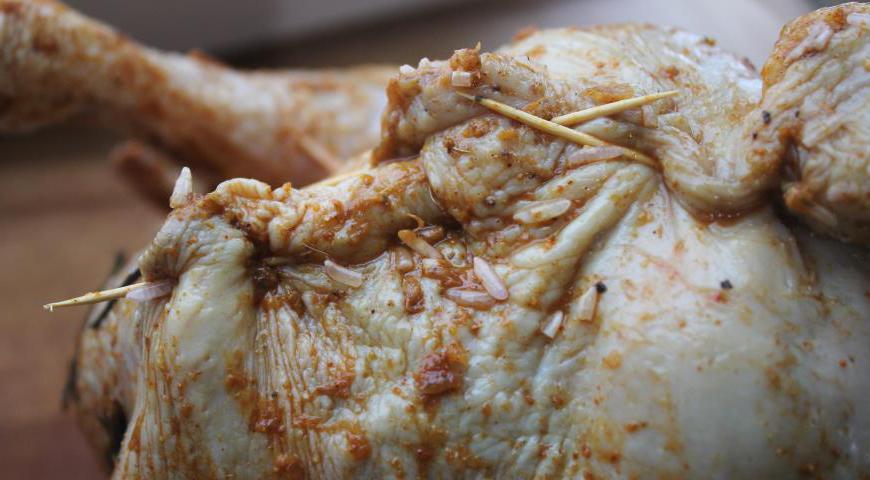 Наполните подготовленной начинкой внутреннюю часть курицы. Не утрамбовывайте слишком плотно, так как рис при термической обработке увеличится в объёме. Закрепите разрез деревянными шпажками, чтобы сохранить форму блюда.