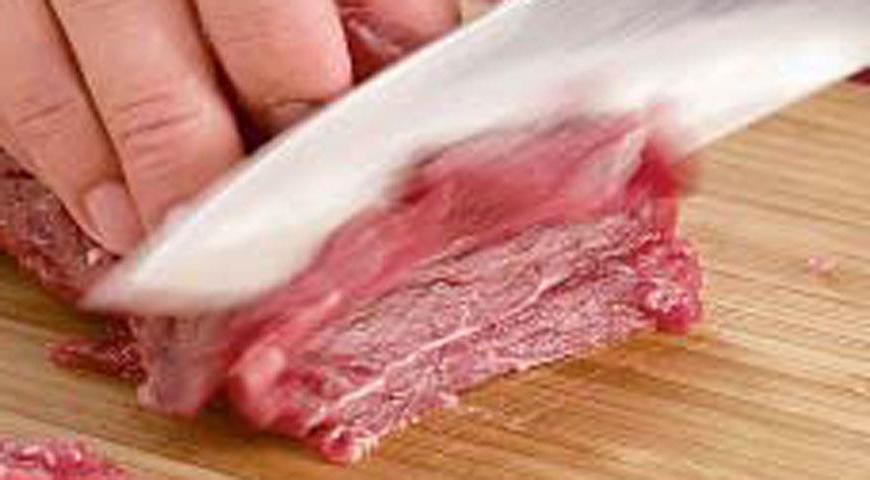 Чуть подморозьте мясо, чтобы легче было его нарезать, затем нарежьте максимально тонкими ломтиками. В большой сковороде разогрейте арахисовое масло и обжарьте лук с чесноком около 40 секунд. Увеличьте огонь до максимума, добавьте мясо и жарьте 1,5 минуты.