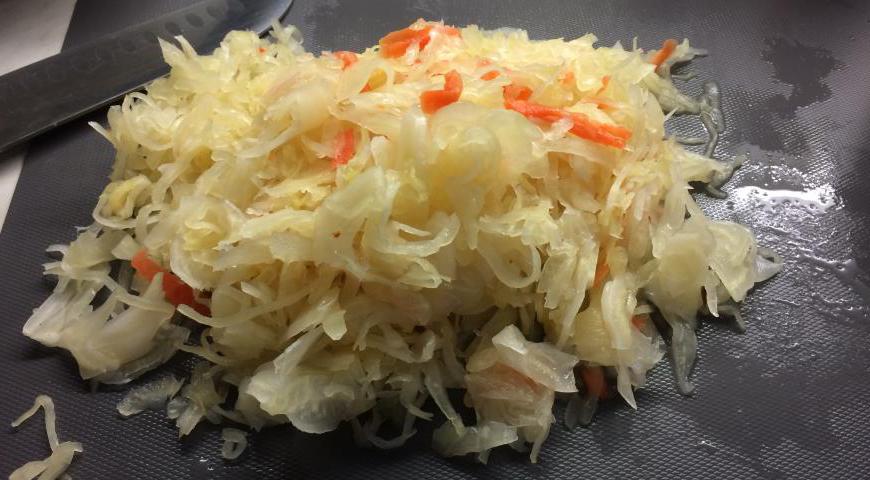 Пока морковь готова, нарезаем квашеную капусту на более удобные кусочки. Не выливаем рассол — он богат полезными бактериями и усилит вкус блюда. Добавляем капусту вместе с соком и морковью в казан.