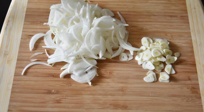 Очистите и нарежьте лук полукольцами, чеснок мелко измельчите ножом или через пресс.