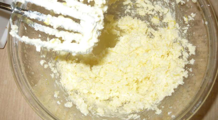 В чаше миксера взбить мягкое сливочное масло с сахаром до воздушной консистенции. Добавить лимонную цедру, сок и ванильный экстракт, продолжить взбивать до однородности.
