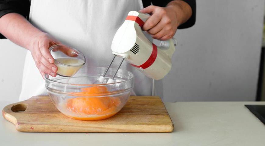 Взбейте яйца с сахаром, солью и сывороткой, которая образовалась при отстаивании ряженки. Добавьте теплый топленый молоко и продолжайте взбивать до однородной массы. Затем постепенно введите просеянную муку и пищевую соду, перемешивая до полной однородности.