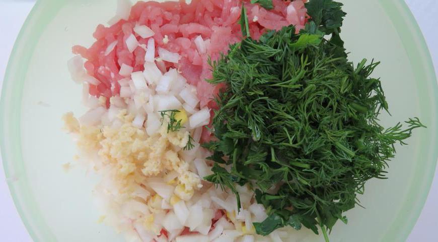 Добавьте нарезанные лук, чеснок и зелень в куриный фарш. Хорошо перемешайте.