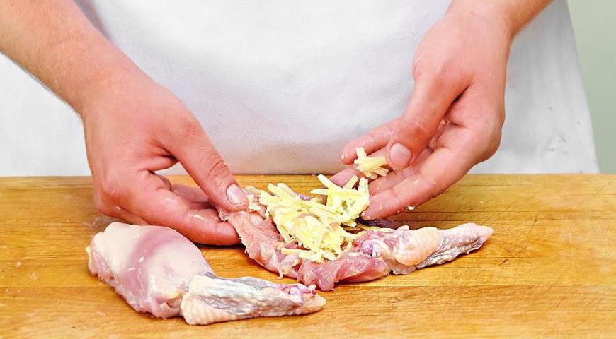 Поделите масло на четыре продолговатых кусочка и натрите сыр на крупной терке, разделив его на четыре части. Обваляйте каждый кусочек масла в тертом сыре. Это предотвратит вытекание масла во время жарки. Разместите начинку по центру каждого филе, присыпав оставшимся сыром.