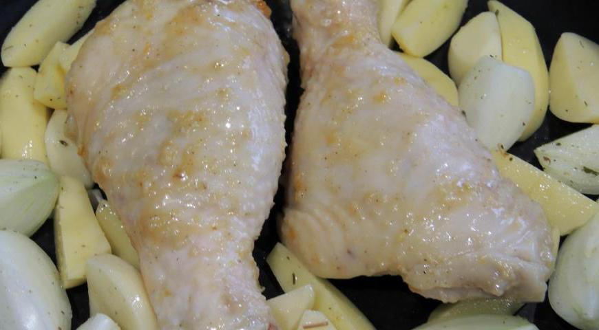 Форму для запекания смазываем маслом, выкладываем голени. Картофель и лук очищаем, нарезаем крупными дольками, немного солим и перчим по вкусу. Раскладываем овощи вокруг мяса. Отправляем форму в предварительно разогретую духовку до 185°C на один час.