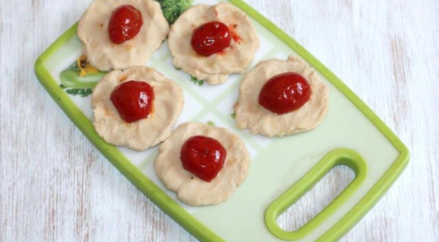 Посыпьте рабочую поверхность мукой и раскатайте каждую часть теста в лепешку. В центр положите дольку вяленого помидора черри.