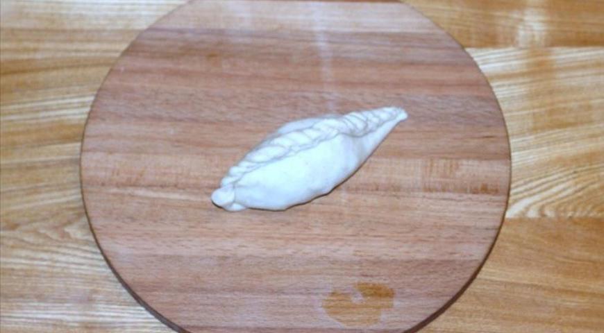 Закройте края теста, защипывая их аккуратно, чтобы получились пирожки. Выложите их на противень, застеленный пергаментом и смазанный растительным маслом. Смешайте сливочное и подсолнечное масло в равных пропорциях и смажьте пирожки этой смесью. Отправьте в предварительно разогретую до 40°C духовку для окончательного подъема.