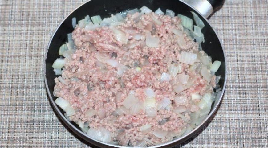 Добавьте мясной фарш к луку и обжаривайте до тех пор, пока мясо не побелеет и не потеряет сыроватый вид.
