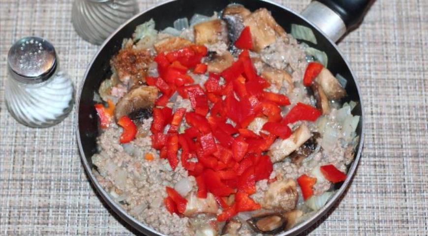 Через пару минут добавьте сливочное масло (15 г), нарезанный кубиками болгарский перец, приправу для мяса, молотый перец и соль. Тщательно перемешайте и продолжайте готовить до полной готовности начинки.