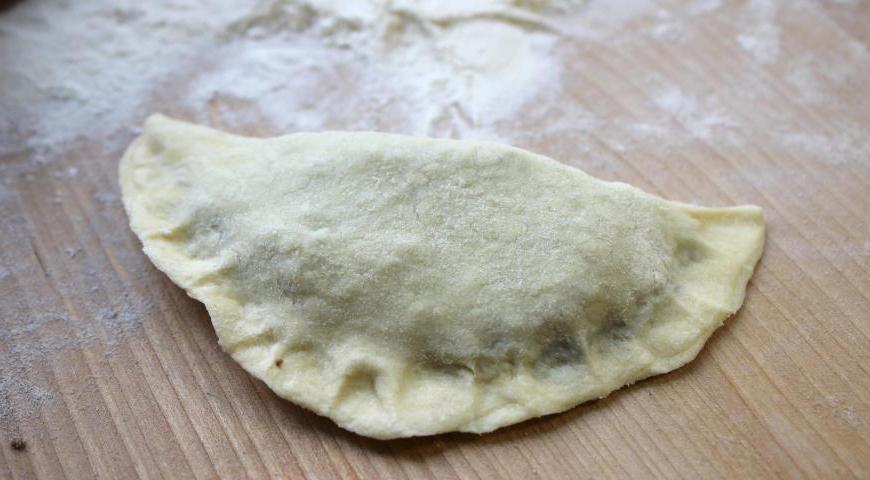 На каждый кружок теста выложите начинку, аккуратно защипните края, формируя пирожки. Уложите изделия на противень, смазанный растительным маслом.