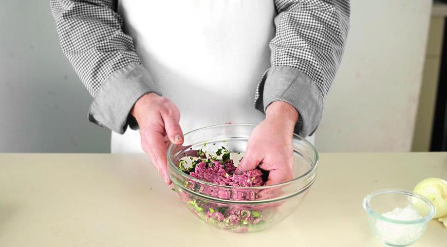 Нарежьте мясо говядины и свиное сало на небольшие кусочки, затем пропустите через мясорубку. Измельчите зелень (зеленый лук и петрушку) и чеснок. Смешайте все ингредиенты, добавьте специи, включая соль и перец. Тщательно вымесите руками в течение 6-7 минут. В конце добавьте немного мелко натертого льда для лучшей текстуры. Оставьте фарш в холодильнике на 35 минут.