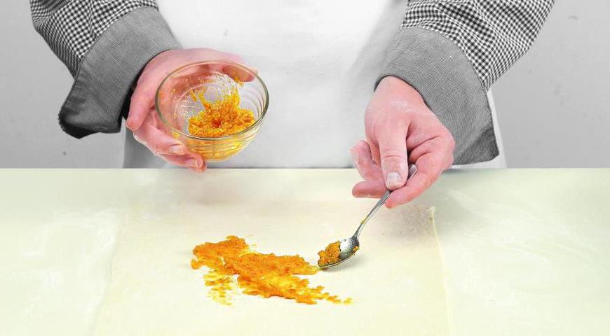 Разогрейте духовку до 185 °C. Раскатайте тесто в пласты, равномерно смажьте пастой из кураги, присыпьте изюмом и сахаром. Сформируйте рулеты, защипнув края.