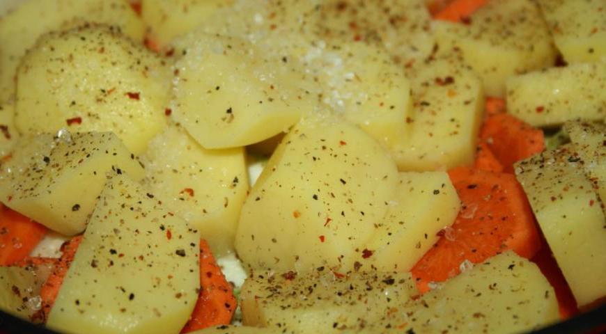 Очистите картофель и морковь, нарежьте крупными кусками. Выложите их на дно казана, слегка посолите и поперчите.