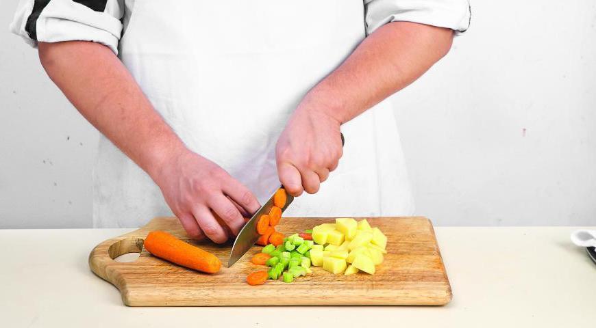 Подготовьте морковь, картофель и сельдерей, порезав их крупными кусками. После готовности лука добавьте овощи в кастрюлю и продолжайте жарить еще 12 минут, периодически помешивая.