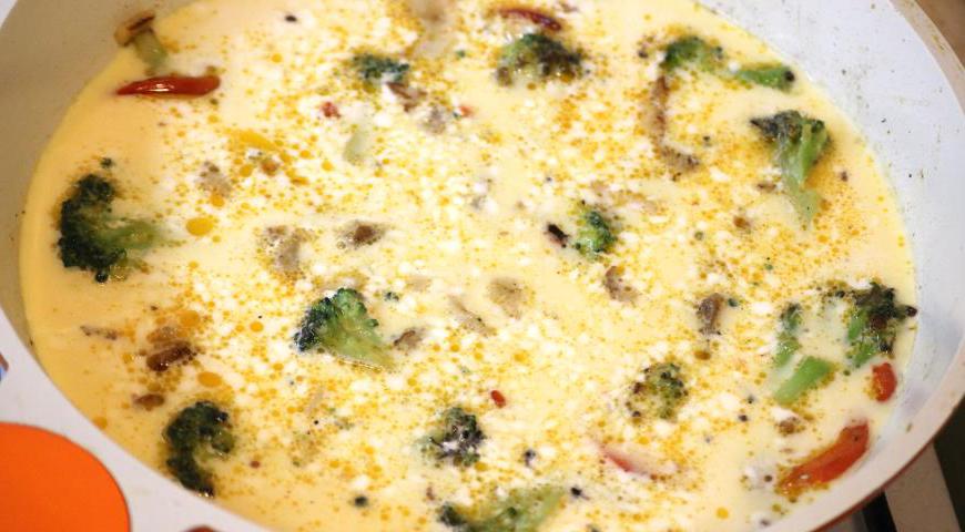 Залейте яичной смесью овощи с мясом, уменьшите огонь, накройте сковороду крышкой и готовьте 3–4 минуты, пока нижняя часть омлета не схватится.
