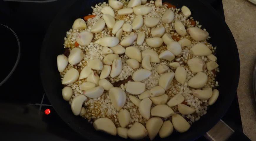 Очистите зубчики чеснока и аккуратно выложите их на слой риса.