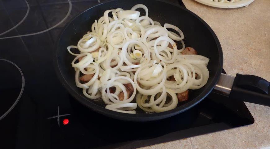 Выложите лук в казан к мясу. Продолжайте жарить, следя за тем, чтобы ингредиенты не теряли своей структуры.