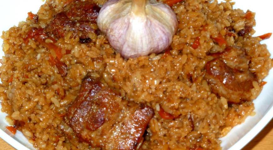 Перед подачей аккуратно перемешайте плов или красиво уложите рис горкой, а мясо с чесноком разместите сверху. Это создаст эффект праздника и подчеркнет восточное происхождение блюда.