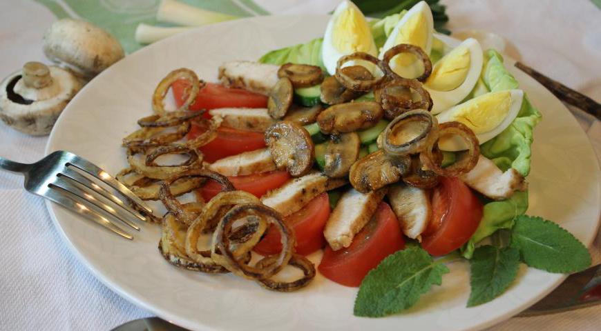 На плоскую тарелку выложите листья салата, сверху разместите мясо, грибы, овощи и яйца. Полейте всё приготовленным соусом и украсьте хрустящими луковыми кольцами. Приятного аппетита!