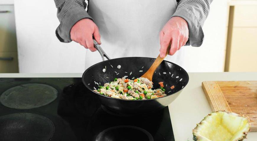 Добавьте еще масло в сковороду. Обжарьте зеленый лук и чеснок до мягкости. Влейте половину яиц и жарьте без перемешивания около 40 секунд. Добавьте рис, свинину, морковь, горошек и оставшиеся яйца. Посолите, поперчите, добавьте специи и готовьте 6-8 минут, пока все не станет однородным.