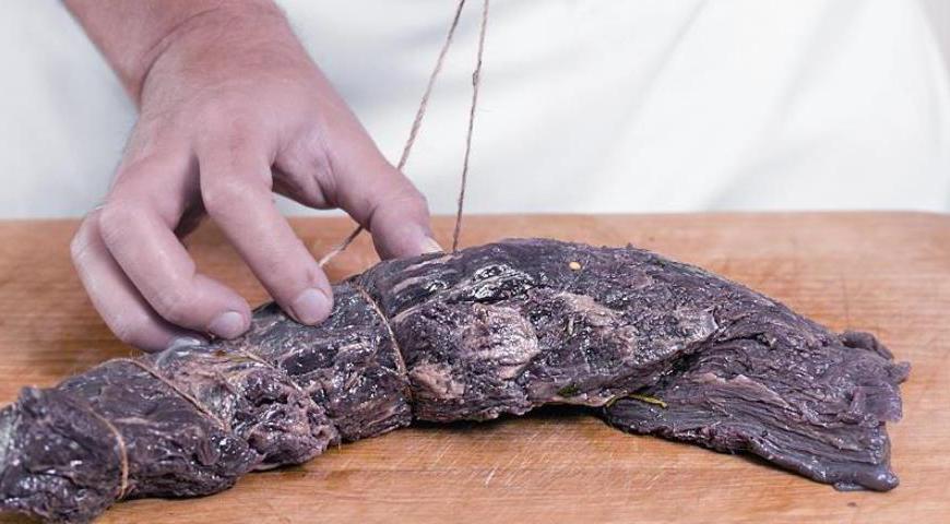 По истечении маринадного периода аккуратно стряхните остатки специй с мяса (не смывайте их водой). Сформируйте плотный кусок и обвяжите его пищевой бечевкой или кулинарным шпагатом.