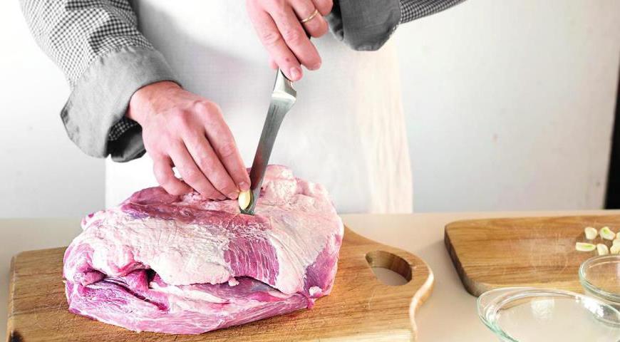 Снимите лишний жир и пленки с окорока. Сделайте проколы на мясе длинным ножом и аккуратно вставьте в них подготовленный чеснок. Повторите процедуру до тех пор, пока всё мясо не будет равномерно нашпиговано.