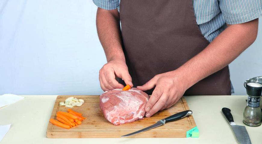 Нашпигуйте мясо: используйте острый длинный нож, втыкая его под углом и поворачивая на 90°. В образовавшиеся отверстия аккуратно вложите подготовленные кусочки чеснока и моркови.