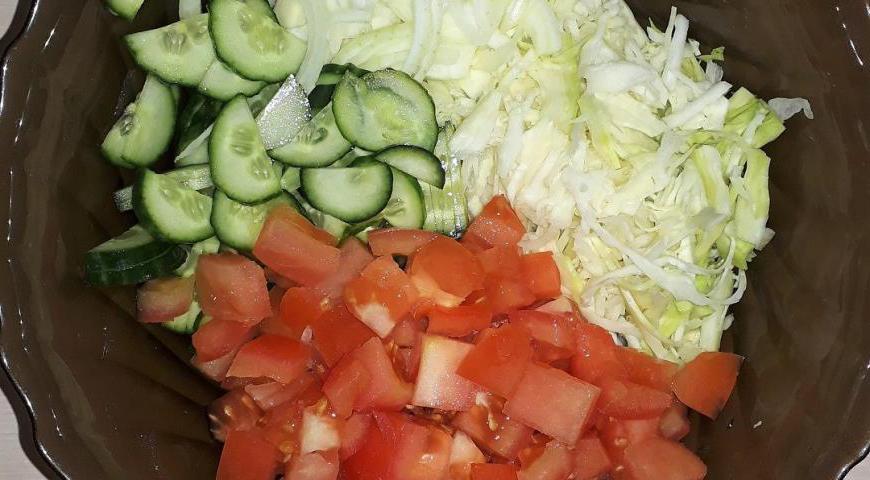 Начнем с подготовки овощей для начинки. Лук нарежьте полукольцами, огурцы — тонкими ломтиками, помидор — небольшими кубиками, а белокочанную капусту тонко нашинкуйте. Сложите все в миску и слегка посолите.