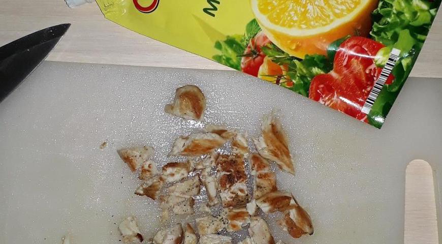 Готовую куриную грудку слегка поперчите и нарежьте небольшими кусочками.