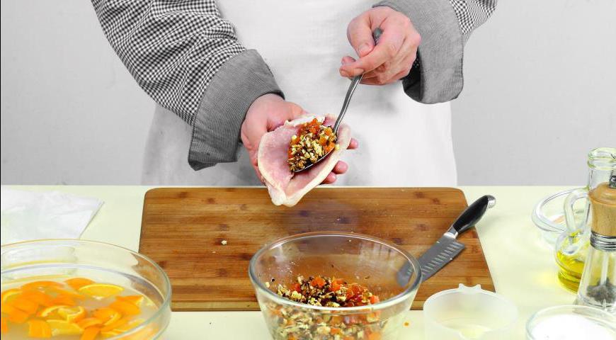 В миске смешайте орехи, курагу, апельсиновый сок и чеснок. Посолите по вкусу, добавьте 2 ст. л. размягченного топленого масла и тщательно перемешайте. Острым ножом сделайте надрез в грудке таким образом, чтобы образовался «карман».