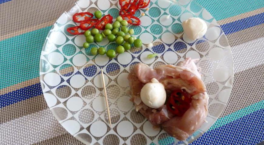 Аккуратно удалите кости из куриных голеней, слегка подрезав мясо по краям. После этого замаринуйте их в смеси лимонного сока, соли, перца чили и приправы для курицы минимум на 3-4 часа. Внутрь каждой голени положите немного зеленого горошка и один шарик моцареллы.
