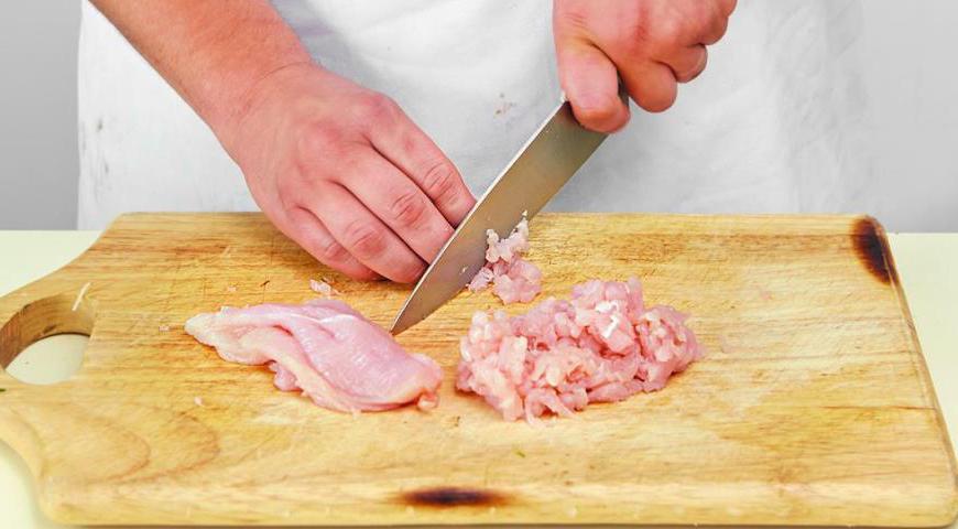 Нарежьте куриное филе небольшими кусочками и пропустите через мясорубку. Лук очистите и мелко нарежьте, затем смешайте с получившимся фаршем.