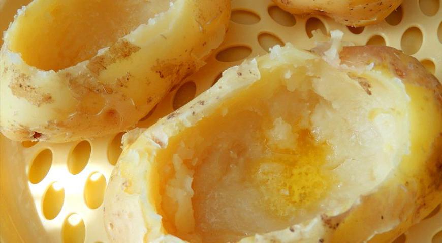 После того как картофель немного остынет, аккуратно выньте середину с помощью чайной ложки. Остальную мякоть разомните или измельчите вилкой.