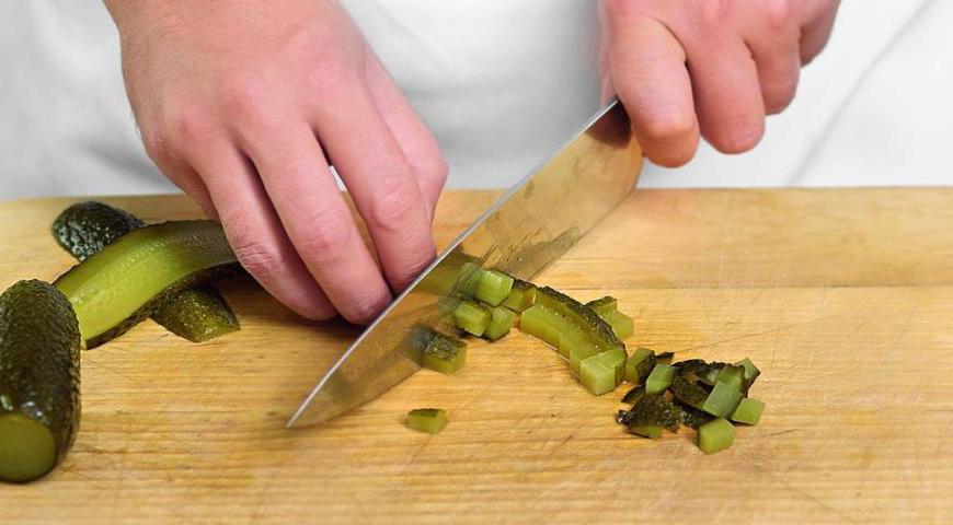 Готовый картофель обдайте холодной водой, чтобы он остыл быстрее. Очистите его и нарежьте на средние дольки. Соленые огурцы также нарежьте мелкими кубиками (при желании можно удалить кожицу).