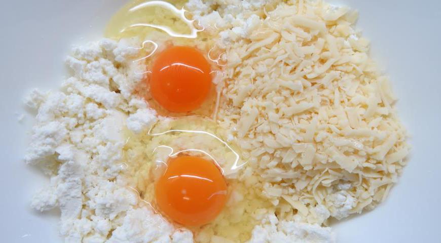 Добавьте к фете творог, предварительно натертый твердый сыр и одно куриное яйцо.