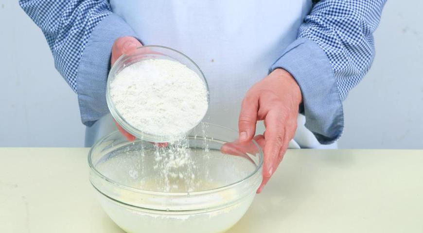 Всыпьте просеянную муку, смешанную с содой и щепоткой соли, в яично-сметанную смесь. Замесите плотное тесто, накройте пищевой пленкой и уберите в холодильник минимум на полчаса.