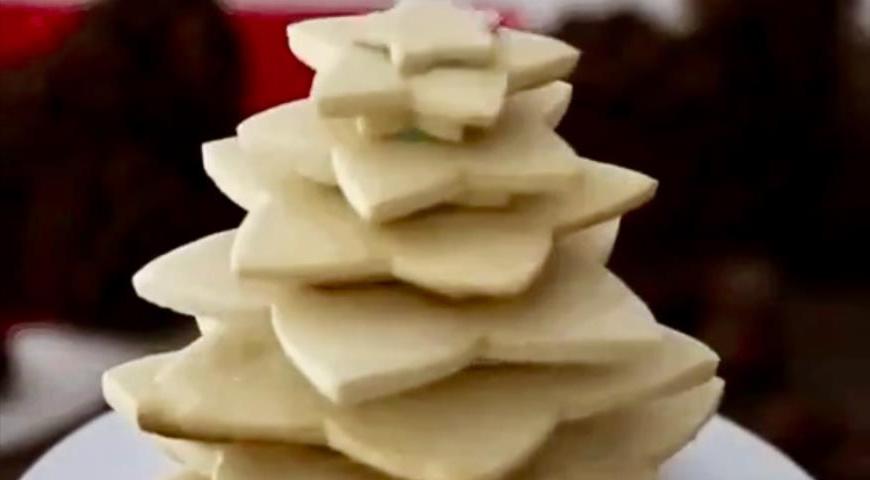 Соберите печенье в виде ёлочки, используя крем как скрепляющий элемент между слоями. Начинайте с самой большой звезды внизу и постепенно уменьшайте размер к верхушке.