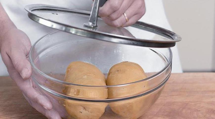 Вымойте картофель щеткой, положите его в кастрюлю с холодной подсоленной водой, доведите до кипения, накройте крышкой и варите около 33 минут. После этого слейте воду, дайте картофелю немного остыть и очистите его горячим от кожуры. Положите картофель в миску, накройте крышкой и оставьте при комнатной температуре на 13 часов. На это же время замочите изюм в роме.