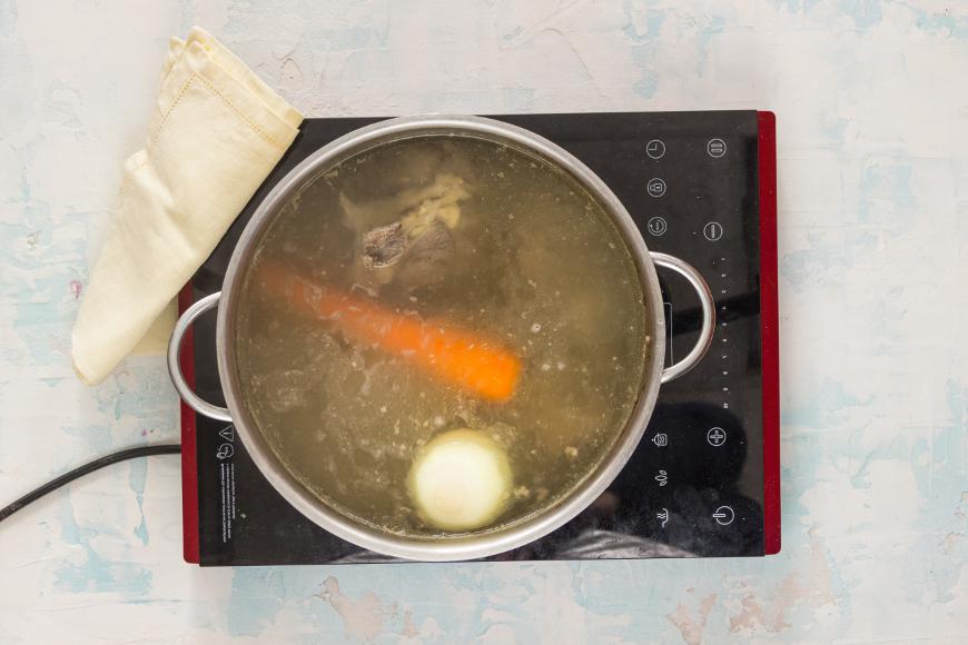 Промойте мясо и кости, поместите их в кастрюлю, залейте 2,2 л холодной воды и доведите до кипения. Удалите пену, добавьте очищенную морковь и луковицу, затем варите около 1,6 часа.
