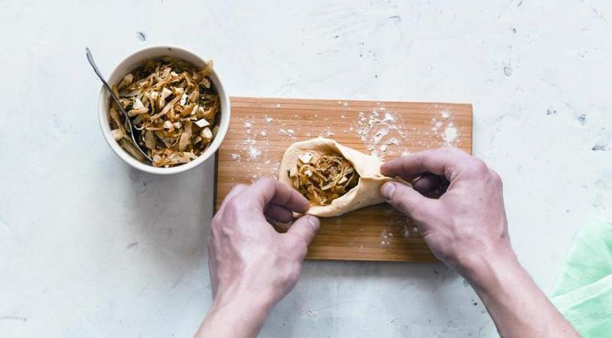 Заполните каждый кусочек теста начинкой, защипните края и расставьте на противень.