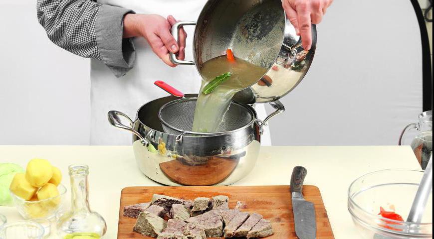 Выньте из бульона мясо, нарежьте на порционные куски и сохраняйте в тепле. Бульон процедите в чистую кастрюлю и поставьте на огонь.