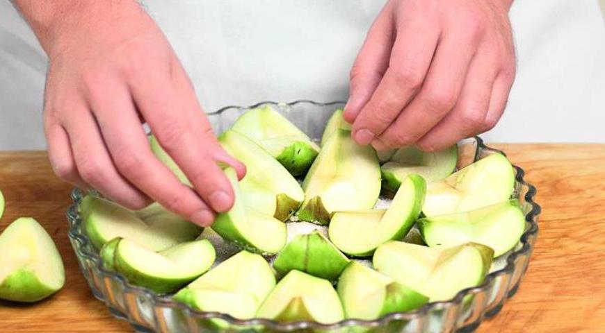 Уложите яблоки плотными слоями кожурой вниз, создавая аккуратный круг. Посыпьте еще полстакана сахара и отправьте форму в духовку, разогретую до 215 °C. Пеките, пока яблоки не станут мягкими и прозрачными, сохраняя свою форму.