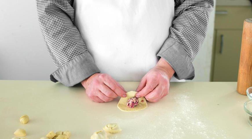 На середину каждой лепешки положите небольшую порцию начинки. Загните края, образуя полукруг, и хорошо защипните края. Убедитесь, что швы плотно закрыты, чтобы начинка не вытекла при варке.