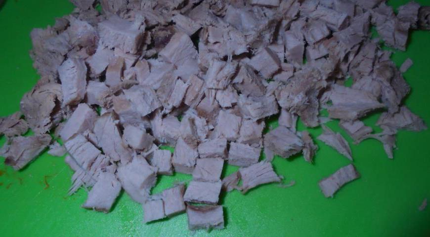 Отварное мясо нарежьте небольшими кусочками и отправьте к овощам и яйцам.